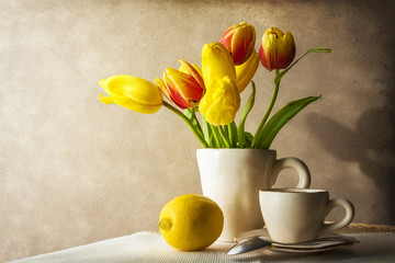 Still life bouquet yellow tulips cup of tea