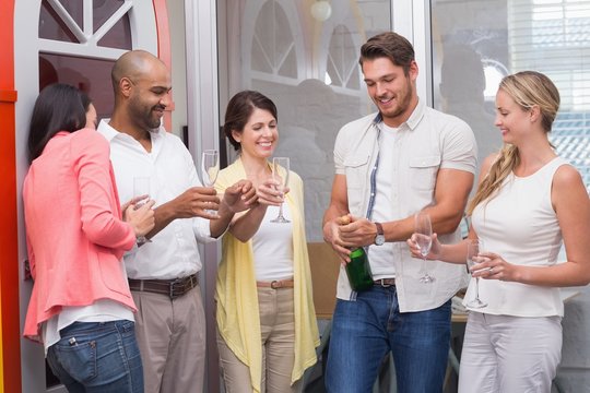 Man Popping Bottle Of Champagne With His Team