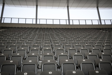 some rows of gray stadium seats, shoot from the front