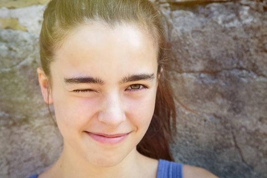 Portrait Of A Smiling Teenage Girl Squinting One Eye