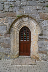 Fototapeta na wymiar A small wooden door, in a stone church wall
