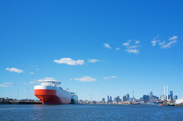 Large cargo ship in Yarra river with Melbourne CBD skyline in th