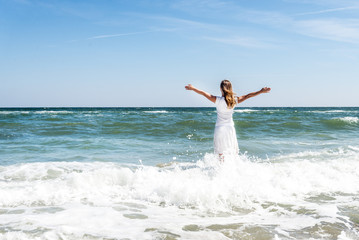Woman in summer dress standing on a sea