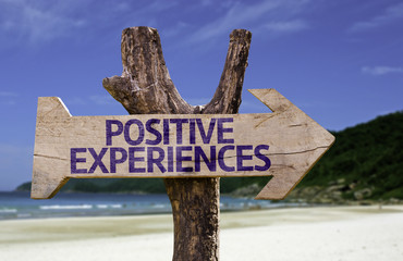Positive Experiences wooden sign with a beach on background