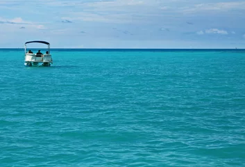 Fotobehang A single pontoon boat in a calm tropical sea © parkerspics