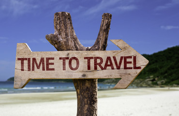 Time to Travel wooden sign with a beach on background