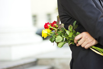 man in a black suit  with a bouquet of roses in hands