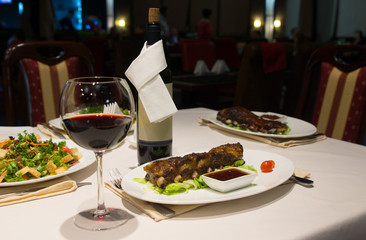 Glass of Red Wine on Table with Plates of Ribs