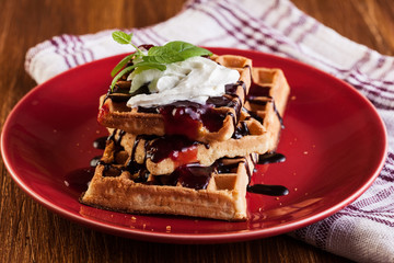 Waffles with chocolate sauce, whipped cream and confiture