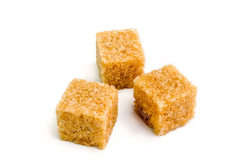 Three cubes of brown sugar with shadow on white background