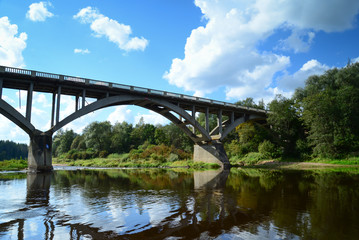 Fototapeta na wymiar river and passing clouds over bridge