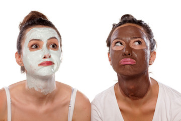 two boring young women with masks posing on white