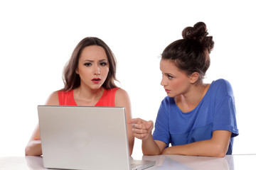 Two young women arguing behind the laptop