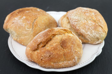 bread on white dish on black background
