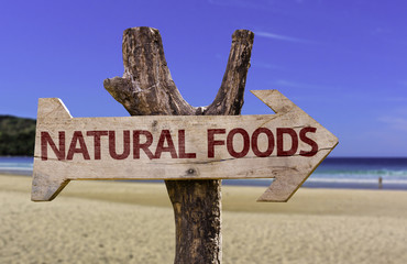 Natural Foods wooden sign with a beach on background