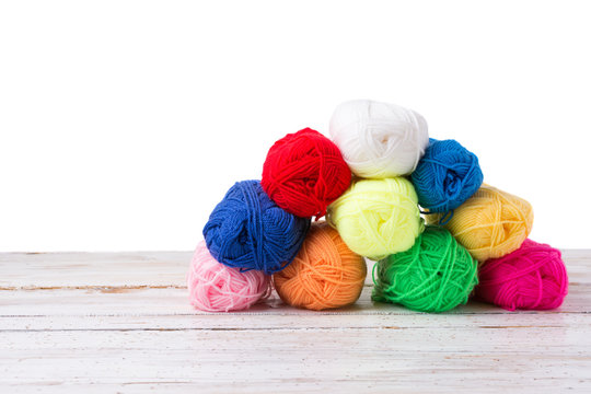 Colorful yarns on white wooden surface isolated