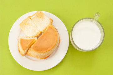 Custard cake and milk on green background.