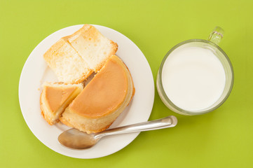 Custard cake and milk on green background.