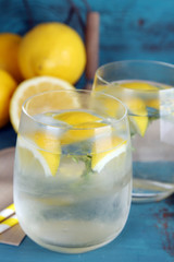 Tasty cool beverage with lemon and thyme, on wooden background