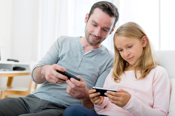 Father and his blond daughter using mobile