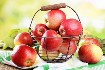 Sweet apples in wicker basket on table on bright background