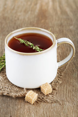 Cup of tasty herbal tea with thyme on wooden table