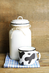 Retro can for milk and mug of milk on wooden table