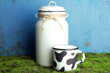 Retro can for milk and mug of milk on wooden background