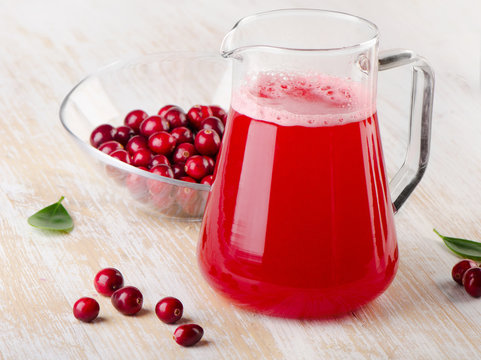 Cranberry drink with fresh berries on a wooden background
