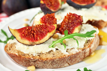 Tasty sandwiches with sweet figs and cottage cheese on plate
