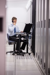 Fototapeta premium Technician talking on phone while diagnosing servers
