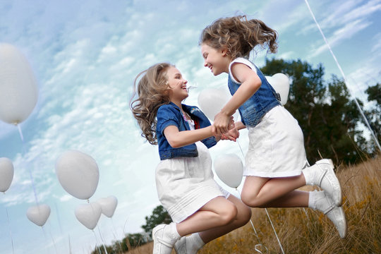 portrait of a little girls in a field with white balloons