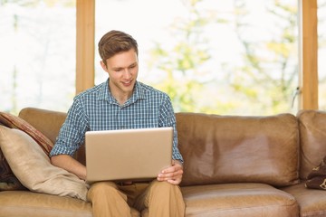 Young man relaxing on his couch with laptop