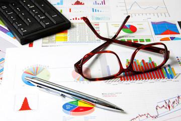 Glasses, numpad and pen on finance chart