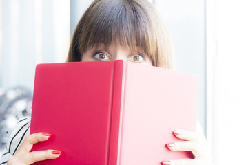 Beautiful woman peeking behind the book