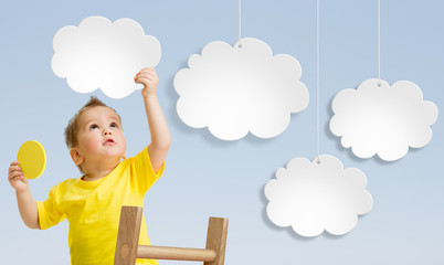 Kid with ladder attaching clouds to sky concept