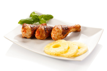 Grilled chicken legs and vegetables on white background