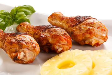 Grilled chicken legs and vegetables on white background