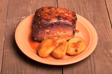 piece of pork, peppers and potatoes in an old wooden table