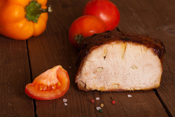 piece of pork, peppers and tomatoes on an old wooden table
