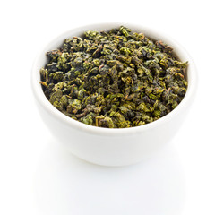Tieguanyin tea leaves in a ceramic bowl on white background