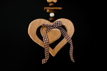 Wooden heart on a rope with wooden balls, a bow in the middle