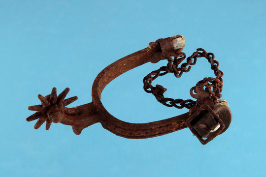 old and rusty riding spur on blue background.