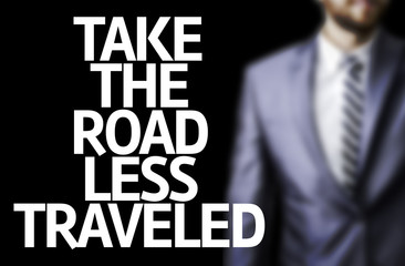 usiness man with the text Take the Road Less Traveled