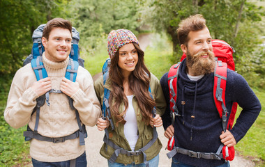 group of smiling friends with backpacks hiking