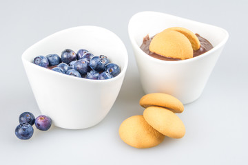 two cups of pudding with blueberries and biscuit