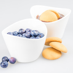 two cups of pudding with blueberries and biscuit