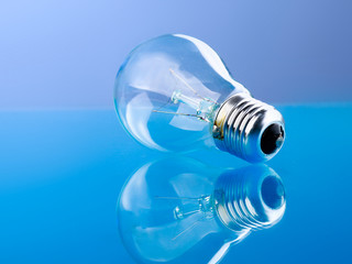 Light bulb isolated on blue glossy background.