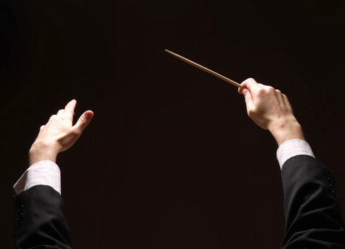 Concert conductor's hands with a baton isolated on a black