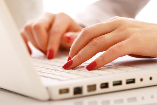 Close-up of businesswoman typing documents on keyboard of laptop